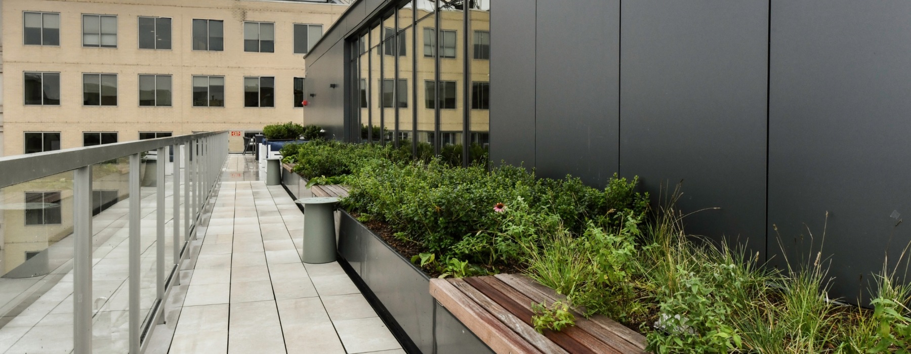 rooftop view of a seating area with lush plants, flowers and cabanas