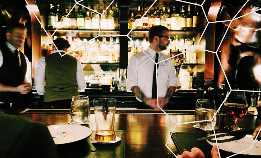 a person in a tie standing behind a bar